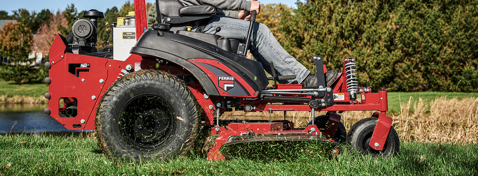 Man on a Ferris zero turn mower with cut grass flying in air next to mower