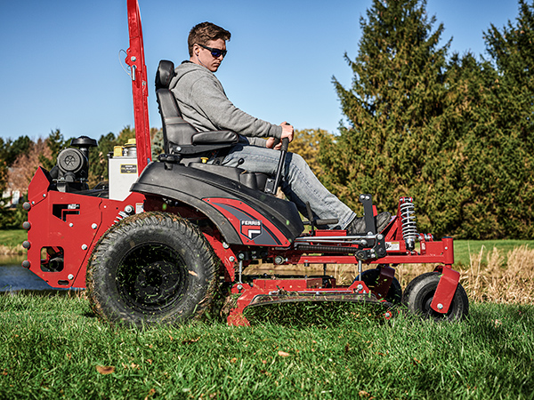 Man on a Ferris zero turn mower with cut grass flying in air next to mower