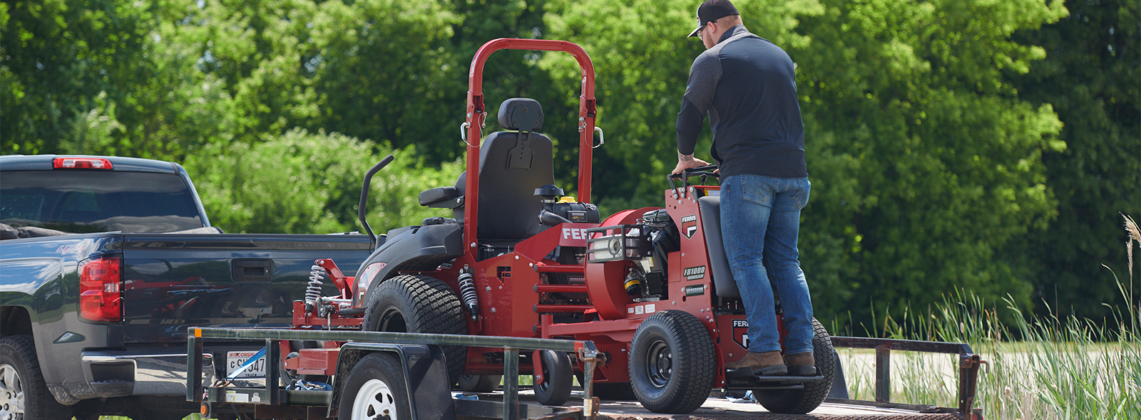 Man loading Ferris stand-on blower onto trailer