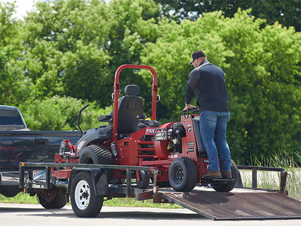 Man loading Ferris stand-on blower onto trailer