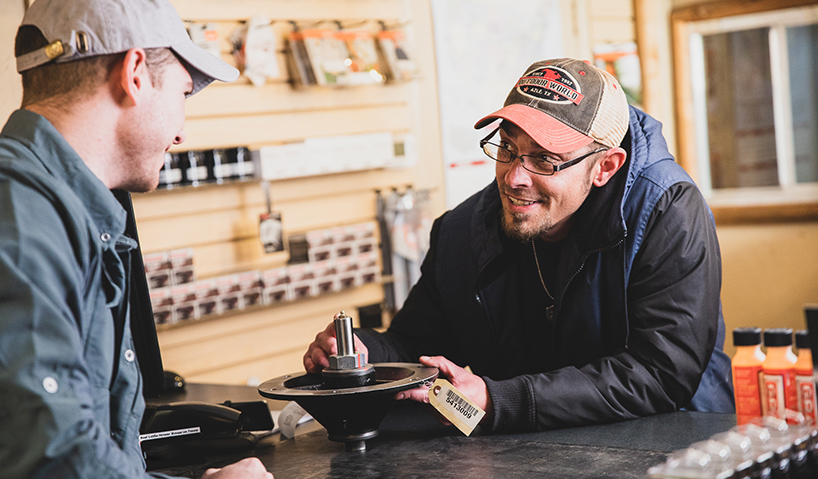 Man holding an engine part talking to a dealer